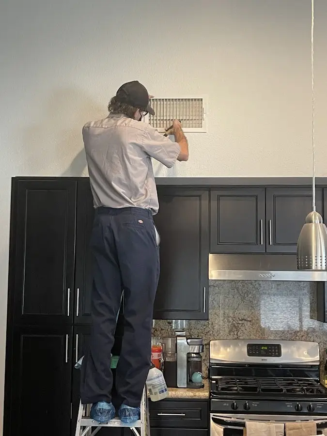 Technician inspecting an air vent during HVAC service in East St. Louis